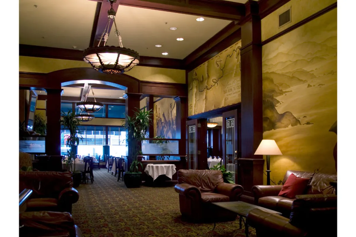 The image features a relaxed lounge area furnished with leather sofas, a decorative mural, and a welcoming dining area. The ambiance is calm yet sophisticated, perfect for recharging after an active day.
